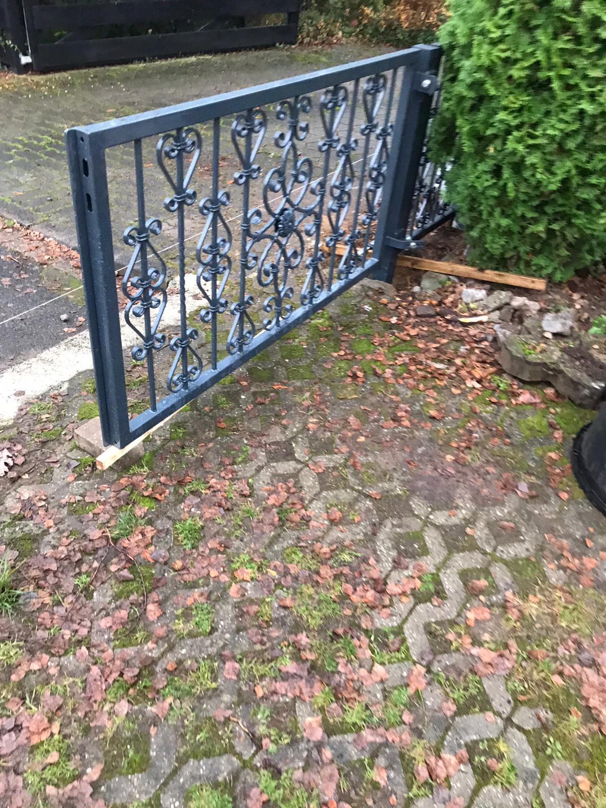 Schmiedeeisernes Gartentor mit Pflastersteinen